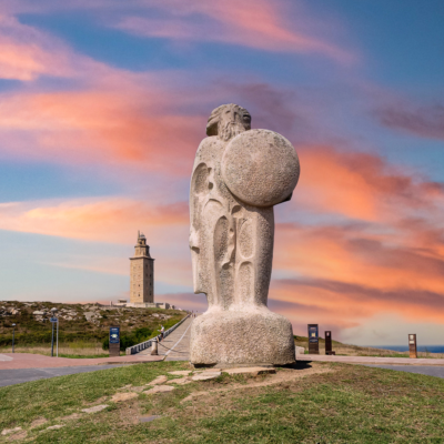 Estatua de Hércules de piedra con la Torre de Hércules en A Coruña (Galicia) de fondo